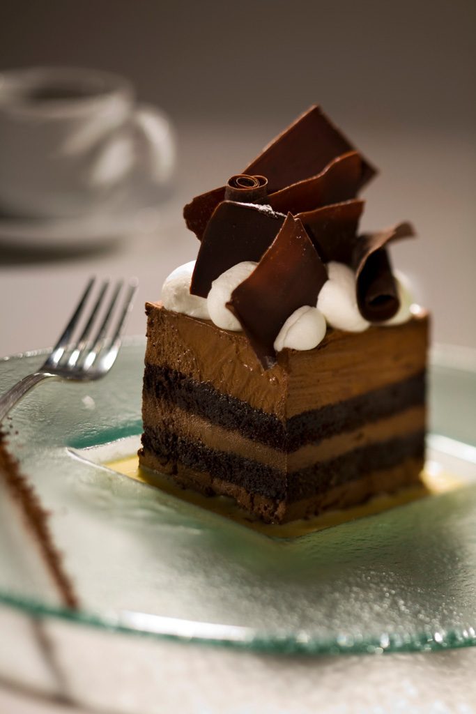 Layered chocolate cake with chocolate curls on a glass plate